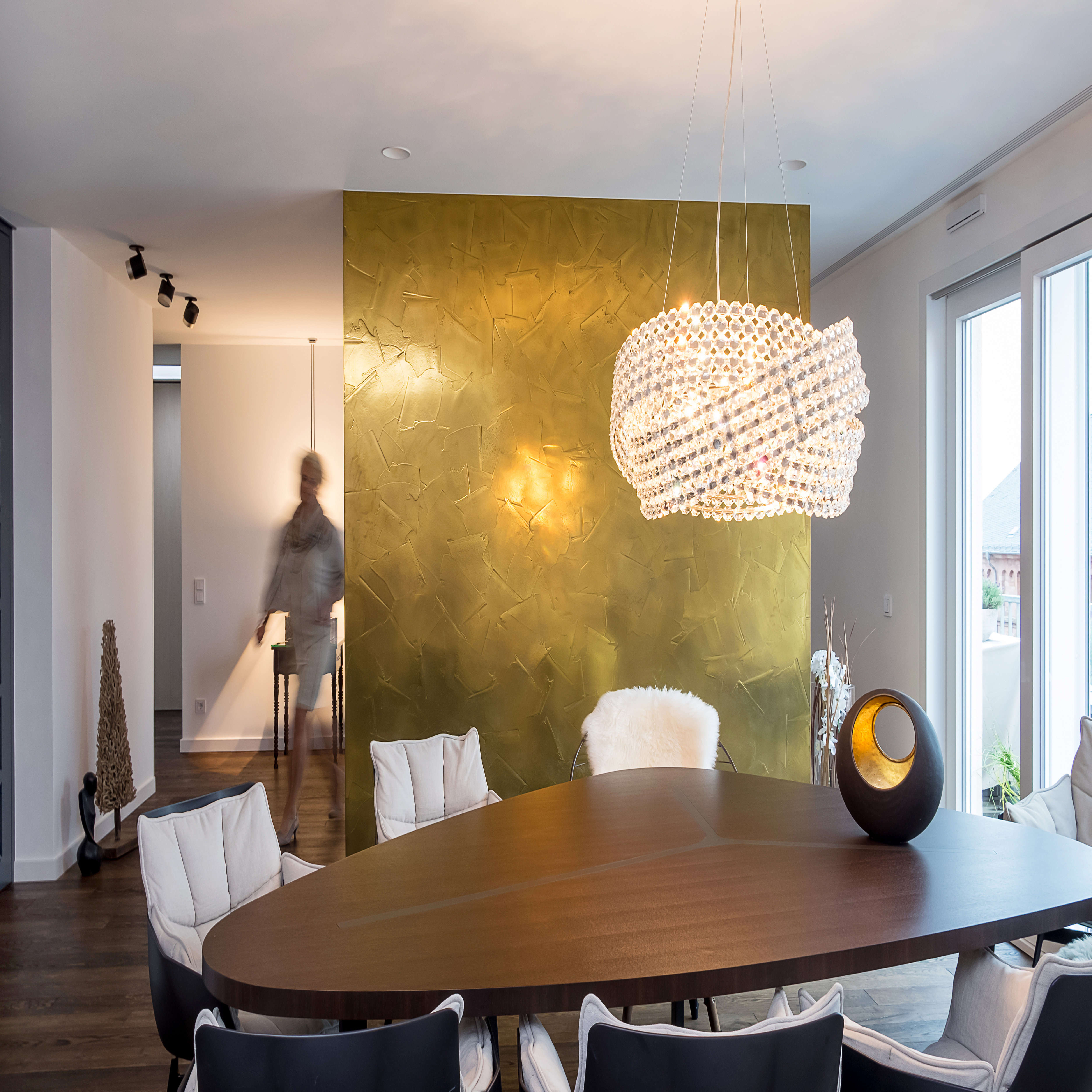 Raum mit modernem, geometrischen Wandgemälde von zwei Gesichtern in bunten Farben, dunkler Holzboden, Geländer im Vordergrund und Deckenleuchten.